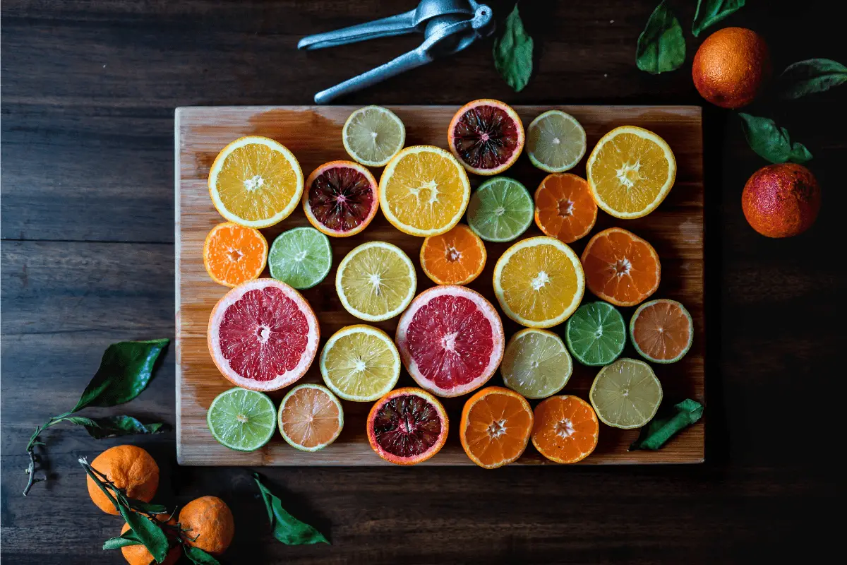 A variety of sliced citrus fruits on a wooden cutting board.