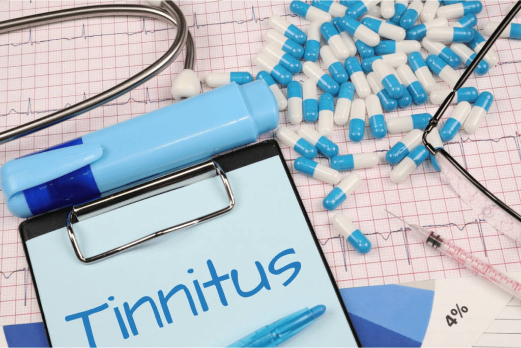 A clipboard with the word “Tinnitus” written on it, surrounded by pills and medical equipment.