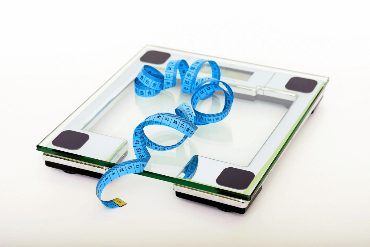 A bathroom scale with a blue measuring tape on top.