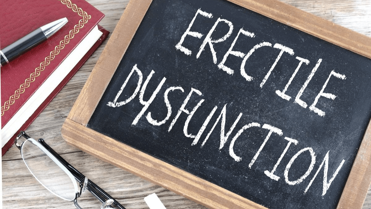 A chalkboard with “Erectile Dysfunction” written on it, with a book and glasses nearby.