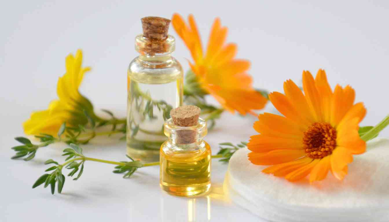 A jar of golden calendula-infused oil sits on a wooden cutting board surrounded by vibrant orange calendula flowers and green leaves. A wicker basket filled with more calendula flowers is in the background.