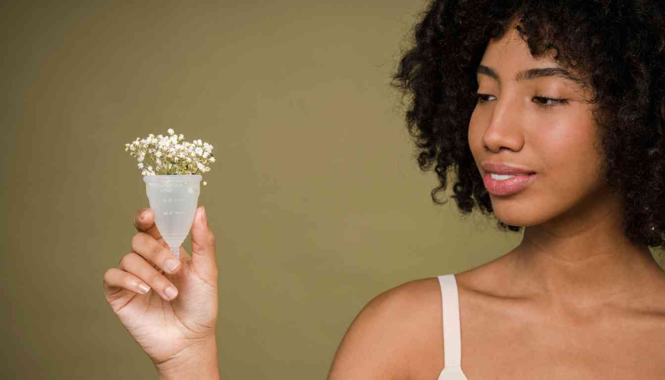 A person holding a small glass period cup with white flowers.