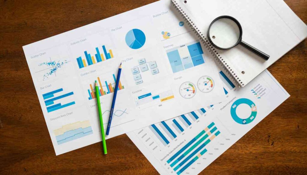 A collection of colorful charts and graphs on a table, with pencils, a magnifying glass, and a notebook placed nearby.