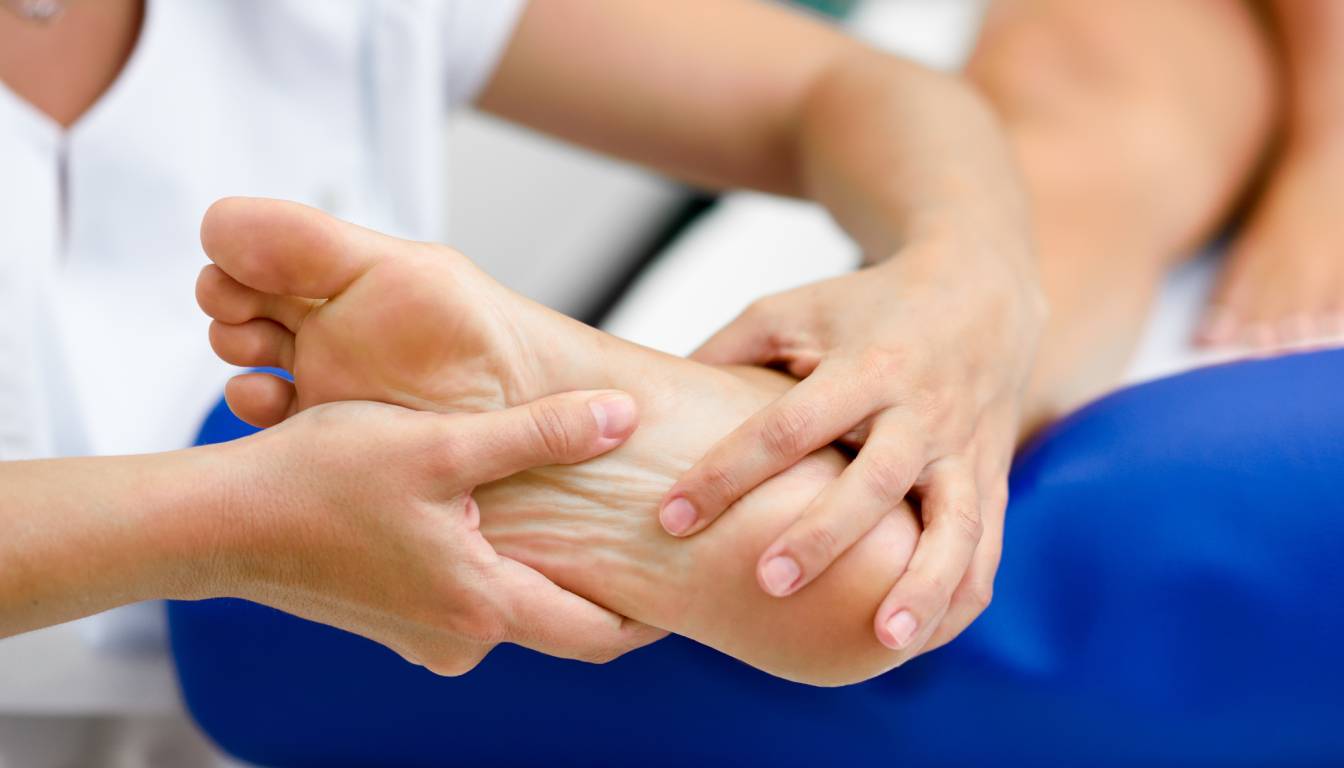 A close-up of a person receiving a foot massage, focusing on the hands of the therapist gently pressing and manipulating the foot.