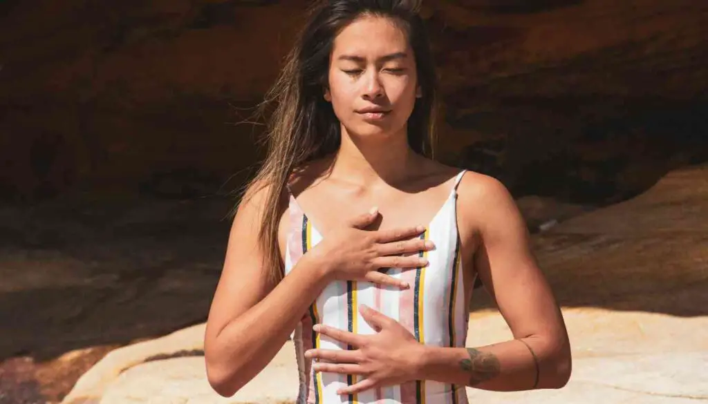 Person holding their chest, possibly indicating heart pain or discomfort, with a blurred background.