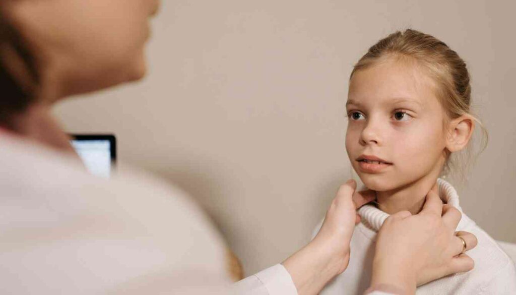 A doctor examining a young girl's throat, likely checking her tonsils.