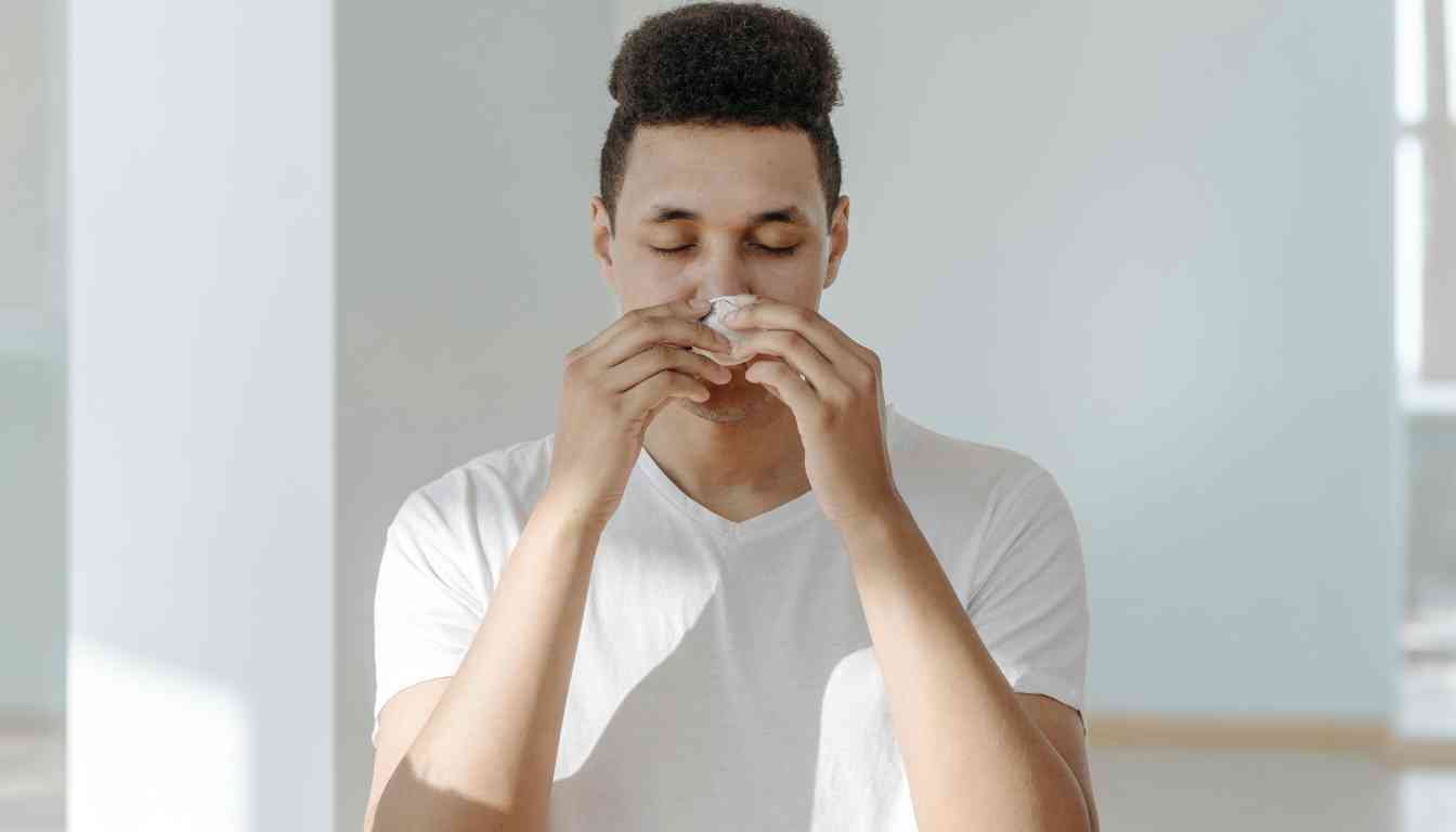 A person in a white t-shirt is holding their hands near their face, possibly demonstrating a home remedy for an upper respiratory infection. The face is blurred out.