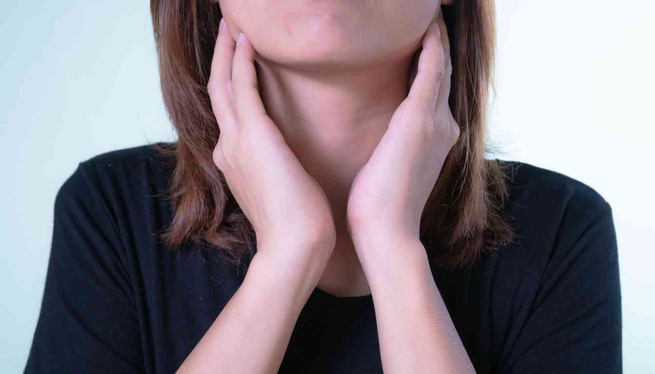 Woman in black shirt touching her throat with both hands, suggesting throat discomfort.