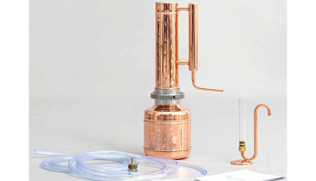 A copper distillation apparatus with various components including tubes and a glass container, used for the distillation of herbs.