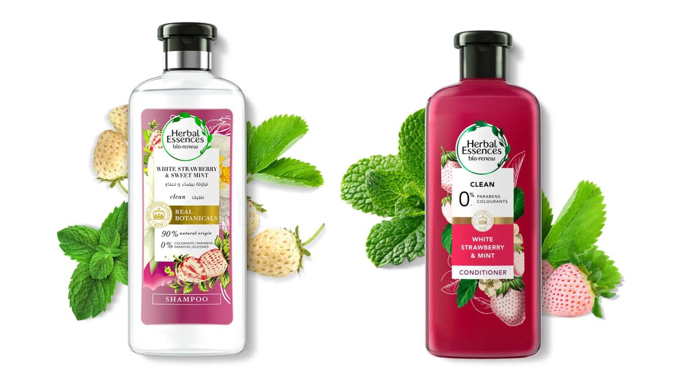 Two bottles of Herbal Essences bio:renew hair care products, featuring the White Strawberry & Sweet Mint Shampoo and Conditioner, surrounded by white strawberries and mint leaves.