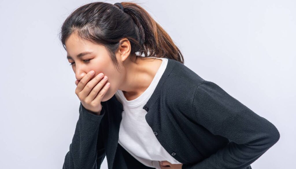 Person clutching stomach and covering mouth, indicating nausea or discomfort.