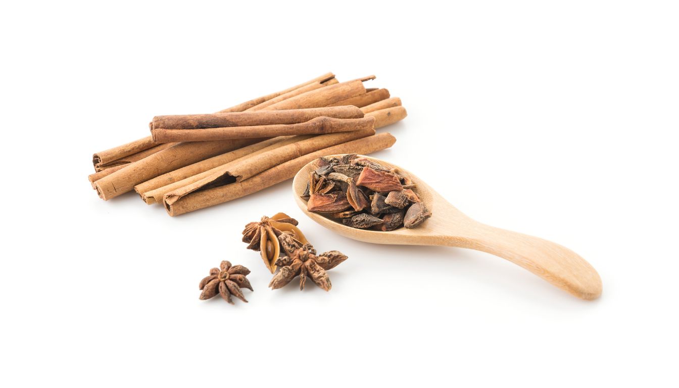 Various herbs and spices, including star anise, fennel seeds, and tarragon, arranged on a white background.