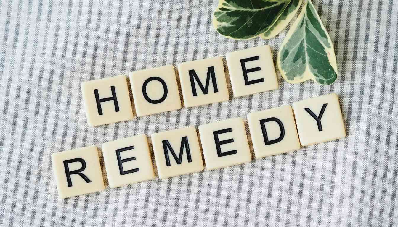 Scrabble tiles spelling out “HOME REMEDY” on a striped fabric background with a green leaf to the side.