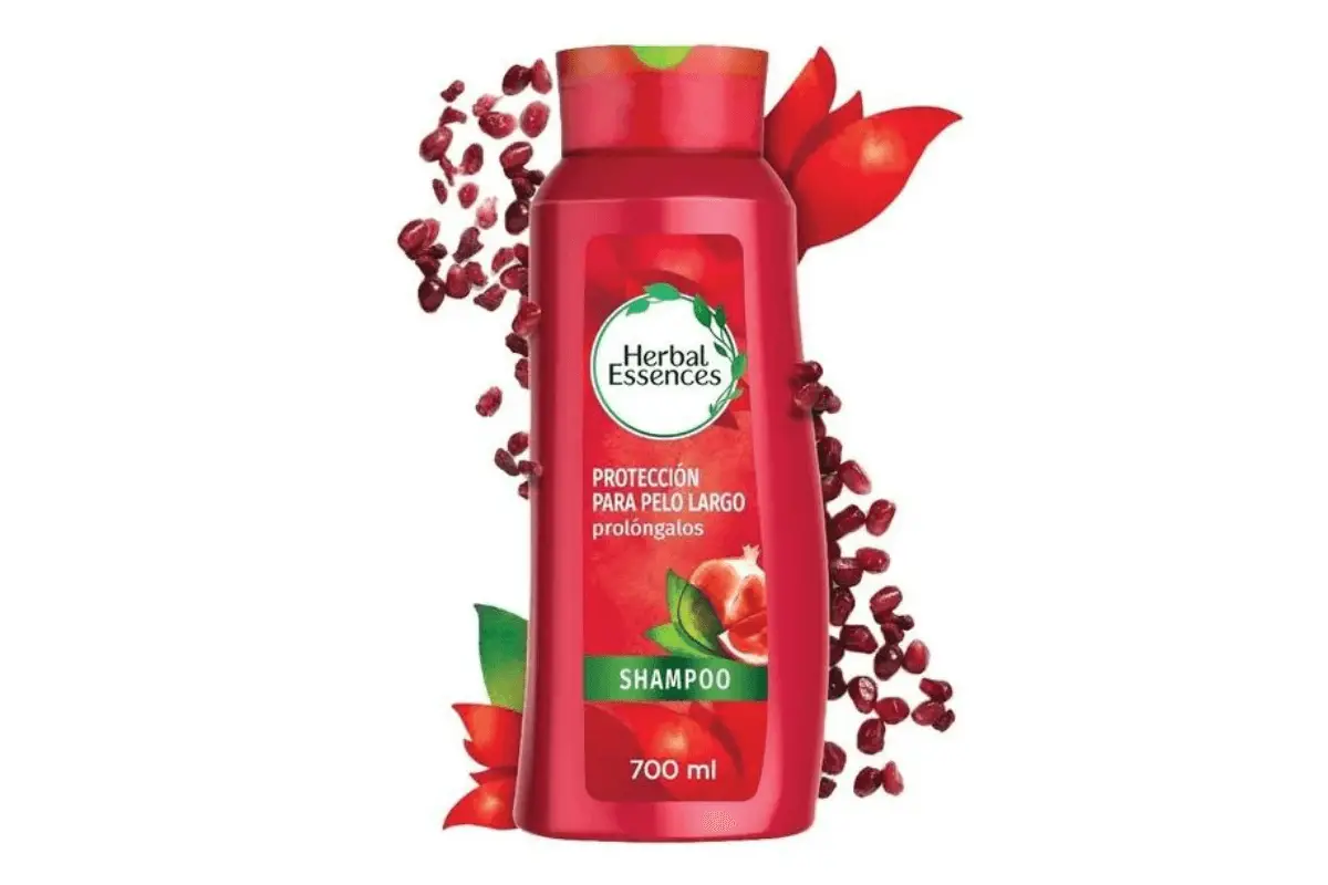 A vibrant image of a 700 ml Herbal Essences shampoo bottle, red in color, surrounded by scattered red berries and leaves, emphasizing its natural ingredients.