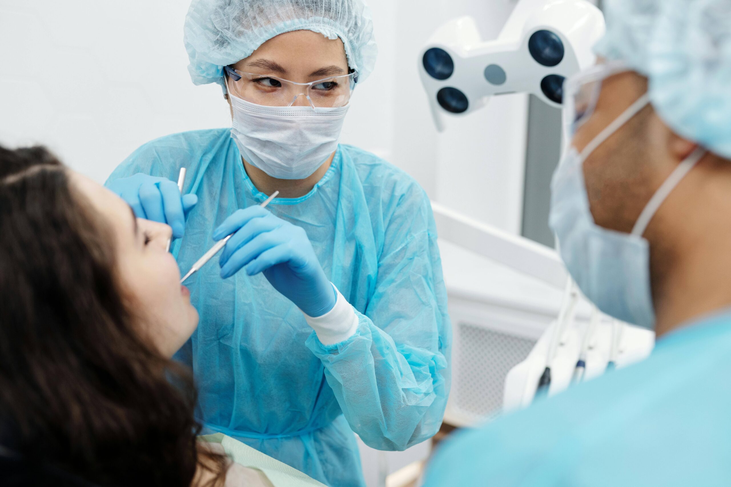 Dental professionals in protective gear performing a dental procedure.