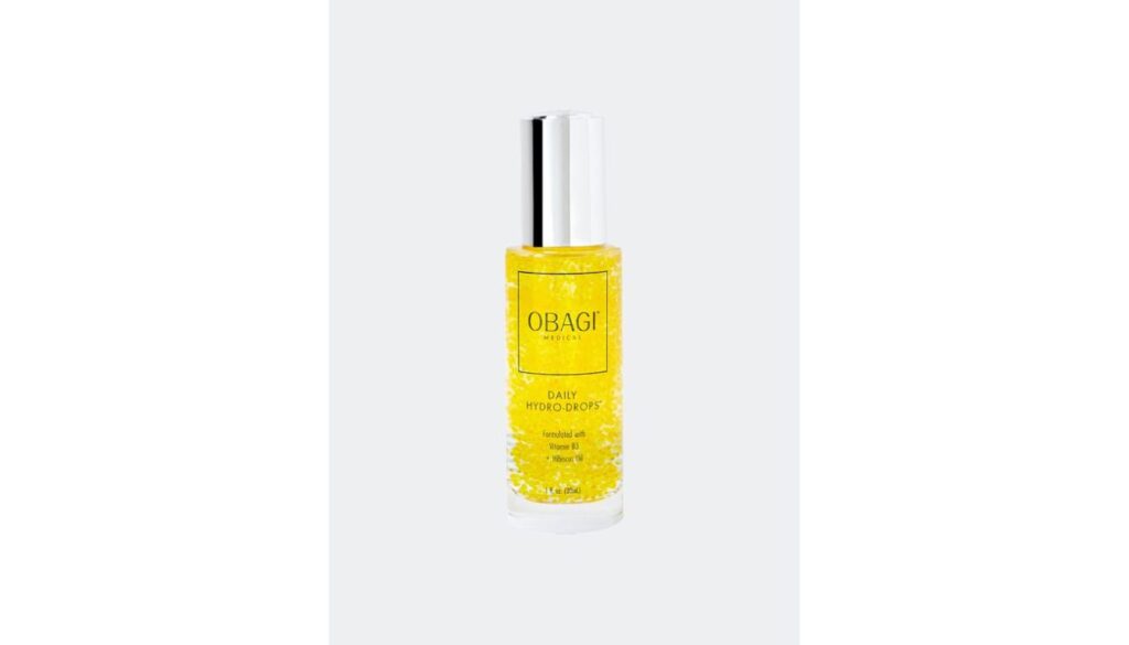 A bottle of Obagi Medical Daily Hydro-Drops, a popular skincare product, with a silver cap and yellow liquid containing visible droplets.