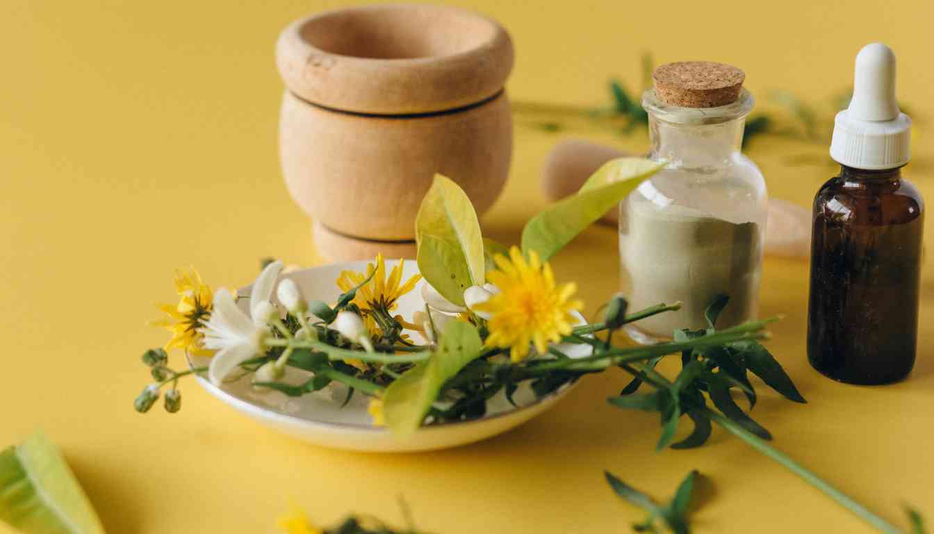 A selection of natural herbal remedies displayed on a yellow background, including a wooden mortar and pestle, a glass bottle with a dropper, and a small jar alongside fresh green herbs and white flowers on a ceramic plate.