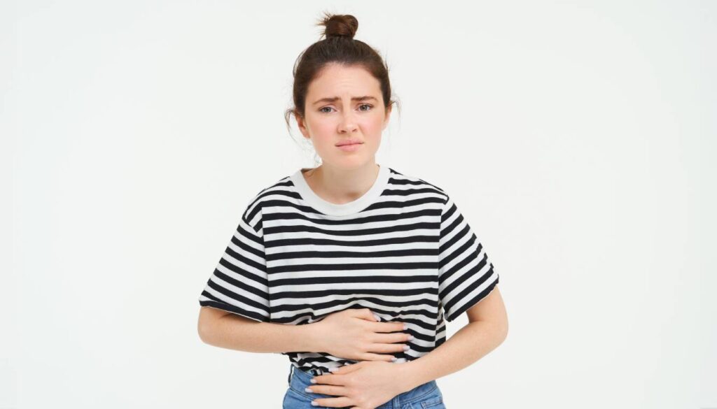 A person wearing a black and white striped shirt holding their stomach, indicating discomfort or bloating