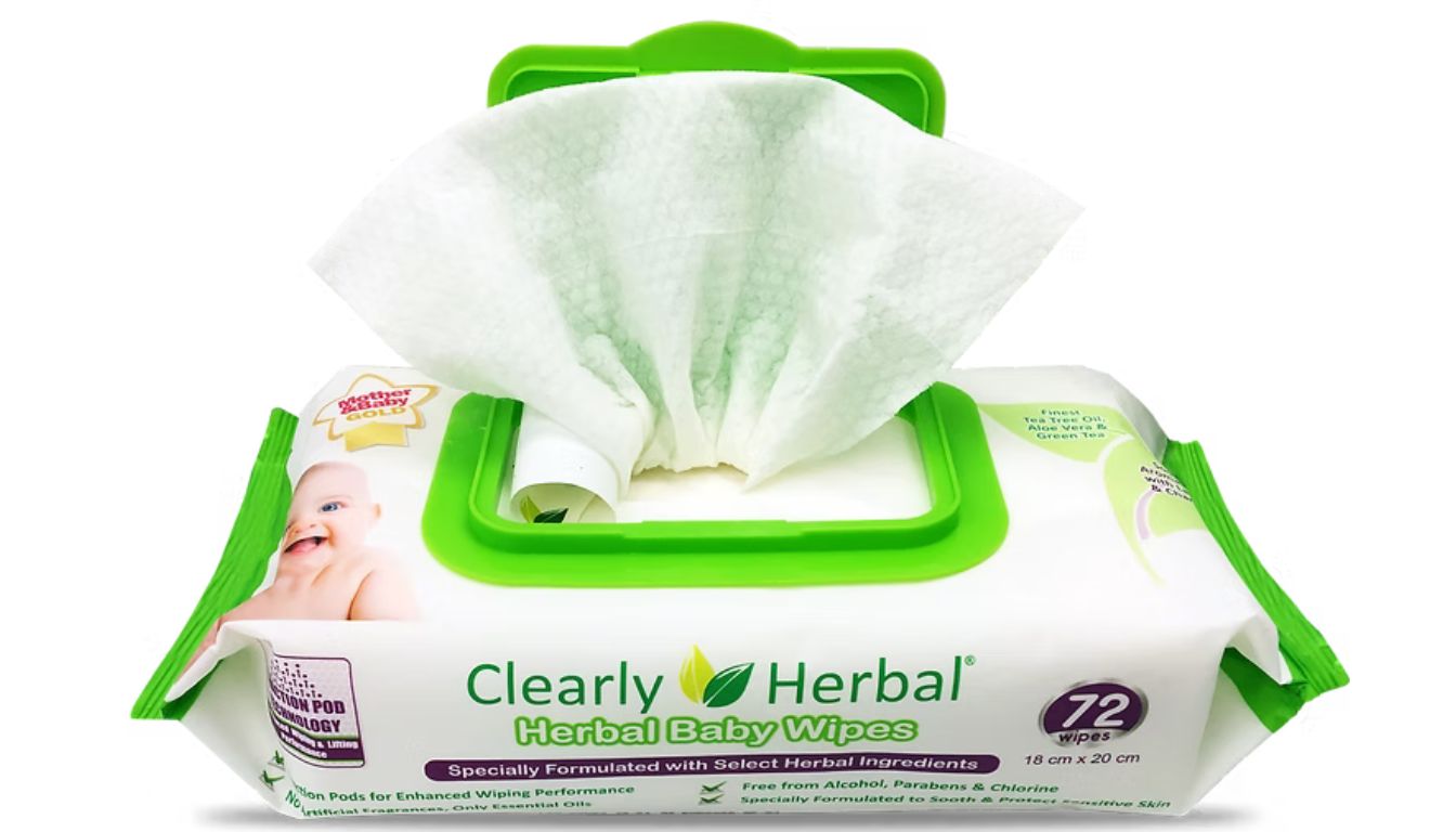 A package of Clearly Herbal Baby Wipes with one wipe partially pulled out from the green dispenser lid. The packaging highlights that it contains 72 wipes and is specially formulated with select herbal ingredients.