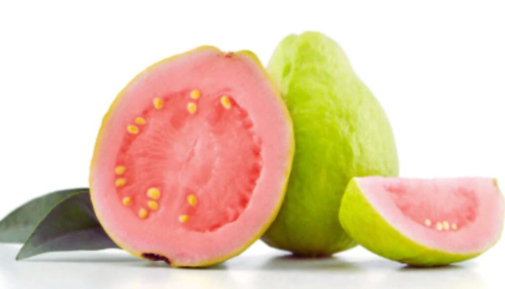 A close-up of a sliced guava fruit showing its pink flesh and yellow seeds, with a whole guava and a guava wedge in the background.