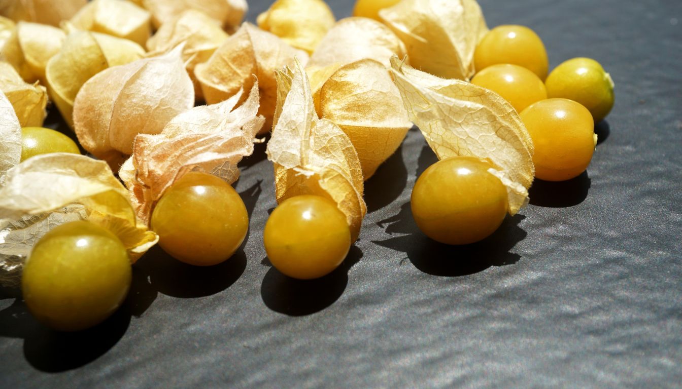 A vibrant image of various ground cherry recipes, featuring sweet and tangy dishes like pies, jams, salsas, and salads, beautifully arranged on a rustic wooden table.