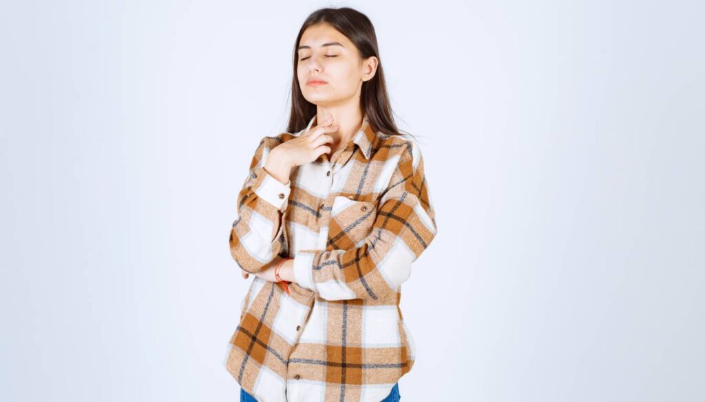 A person in a brown and white plaid shirt with one hand resting on their chin and the other arm crossed