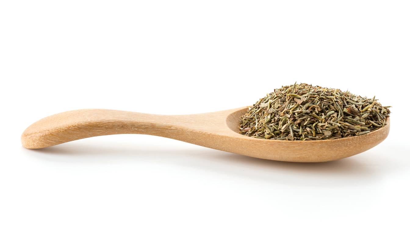 A wooden spoon filled with dried oregano leaves on a white background.