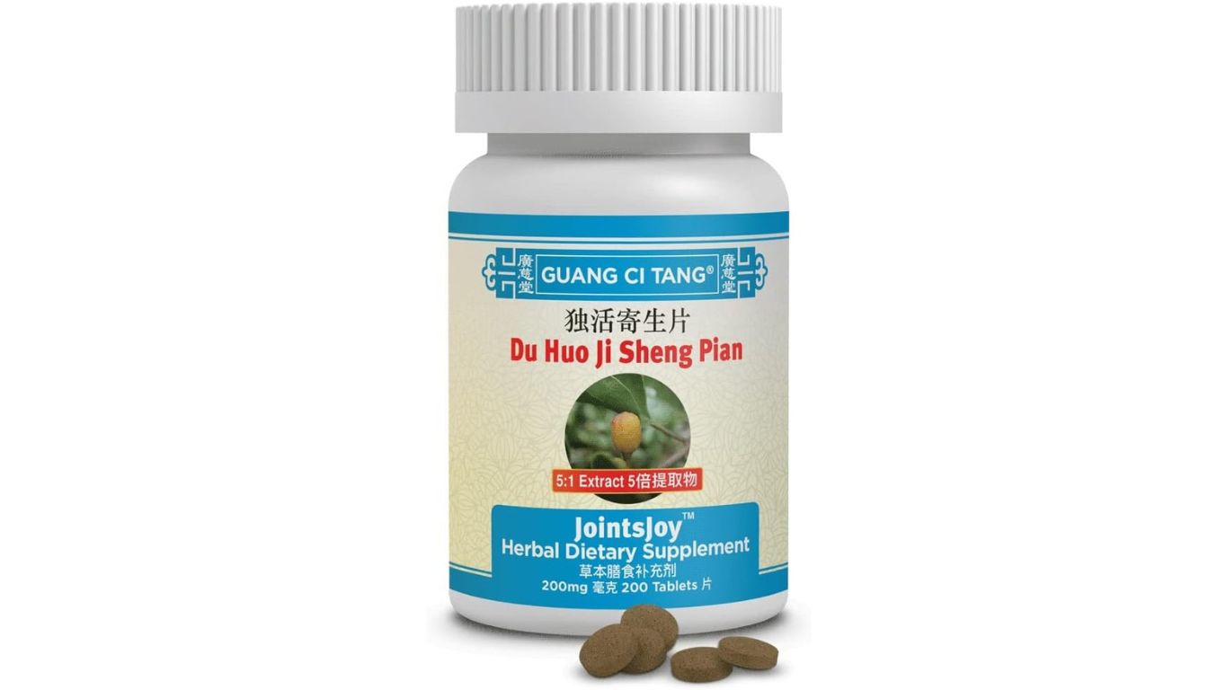 A bottle of Guang Ci Tang Du Huo Ji Sheng Pian herbal dietary supplement, labeled as JointsJoy, with several tablets placed in front of it.