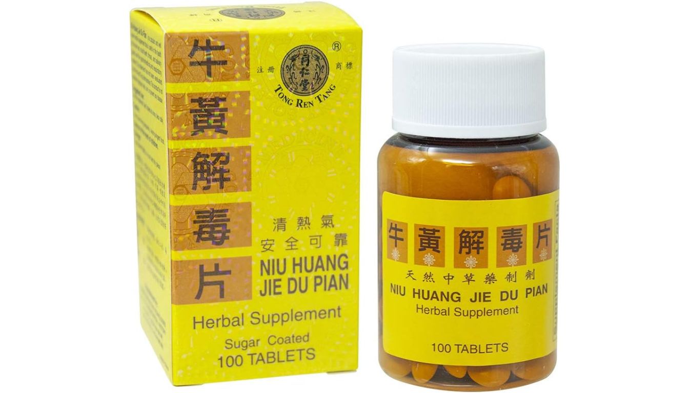 A yellow and orange box of Tong Ren Tang Niu Huang Jie Du Pian herbal supplement, showcasing the product name in both Chinese and English, next to a bottle containing sugar-coated tablets.