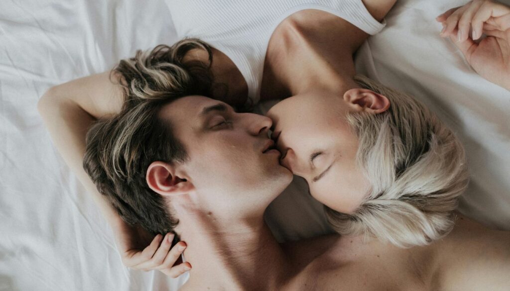 Two young individuals in bathrobes lying on a bed, with the focus on their feet, creating a cozy and intimate atmosphere.