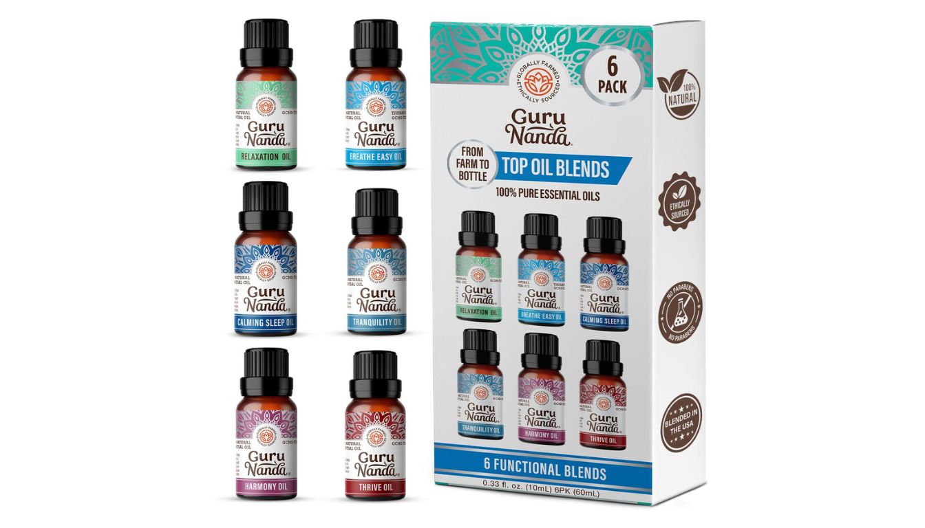 A set of six GuruNanda essential oil blends in small brown bottles with black caps, displayed alongside their packaging box. The box highlights the product's features, including being 100% pure essential oils, ethically sourced, and free from parabens.