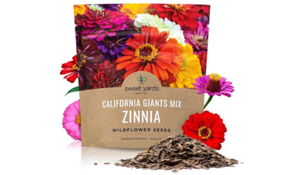 A packet of Sweet Yards California Giants Mix Zinnia wildflower seeds with colorful zinnia flowers and a small pile of seeds in front.
