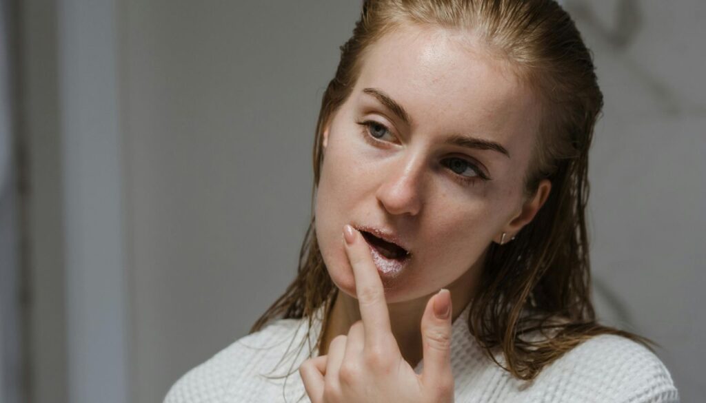 A person applying a DIY sugar lip scrub on their lips, showcasing natural beauty.