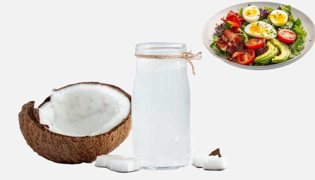 A glass bottle of coconut oil accompanied by a halved coconut and a keto-friendly salad featuring avocado, eggs, tomatoes, and bacon on a white backdrop.