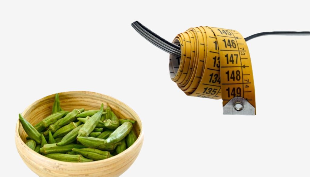 A wooden bowl filled with fresh okra next to a rolled-up measuring tape.