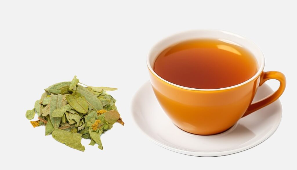 A vibrant orange cup filled with amber Senna tea sits beside a small pile of dried senna leaves.
