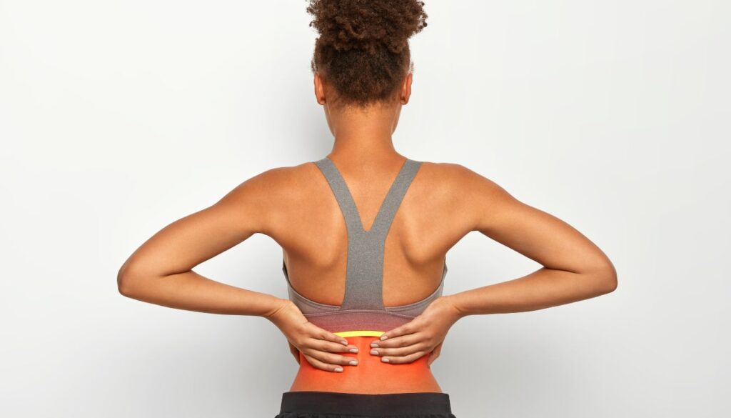 A person holding their lower back suggesting muscle tension and discomfort.