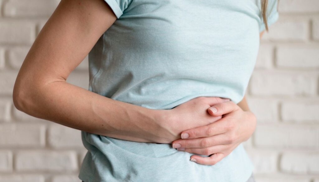 A woman holds her stomach with a pained expression, symbolizing the discomfort of acid indigestion.