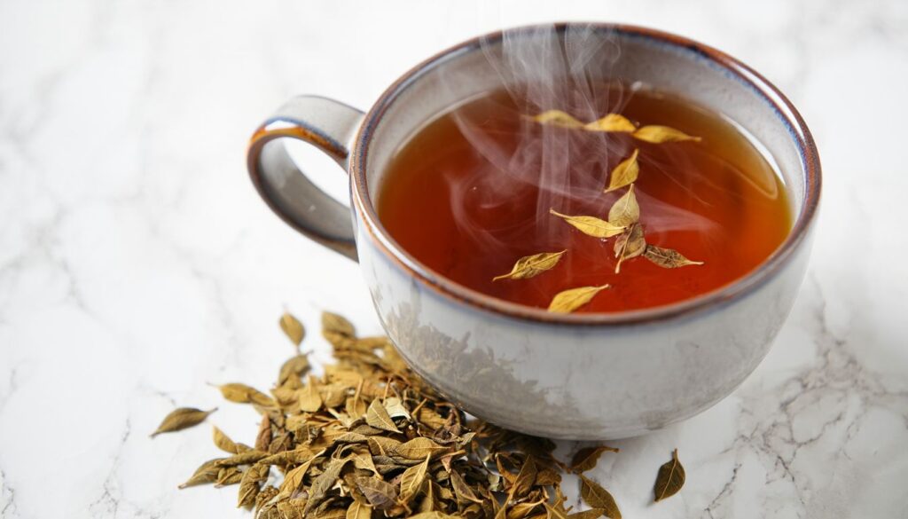 A steaming cup of Eucommia leaf tea placed on a wooden surface, surrounded by dried tea leaves and fresh greenery.