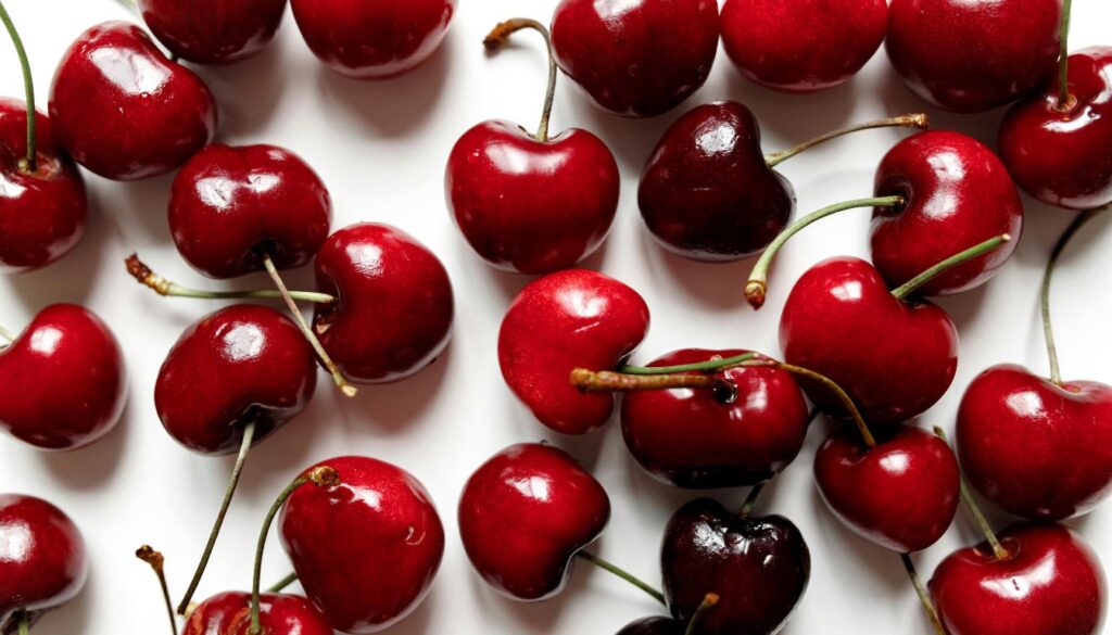 A close-up of red cherries with vibrant hues and fresh green stems.