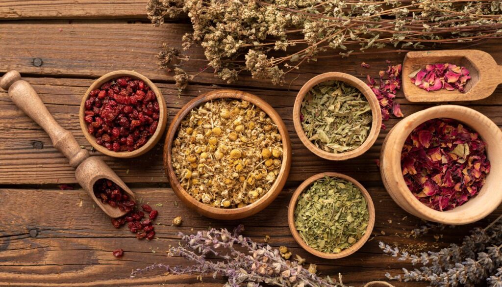 Wooden bowls and scoops filled with dried herbs and flowers on a rustic table, representing traditional Middle Eastern healing practices.