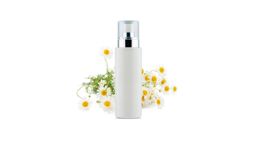 A white cylindrical bottle with a silver and transparent cap, placed in front of white daisies with yellow centers.