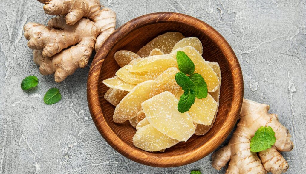 Wooden bowl of homemade herbal cough drops with mint and ginger on a gray surface.