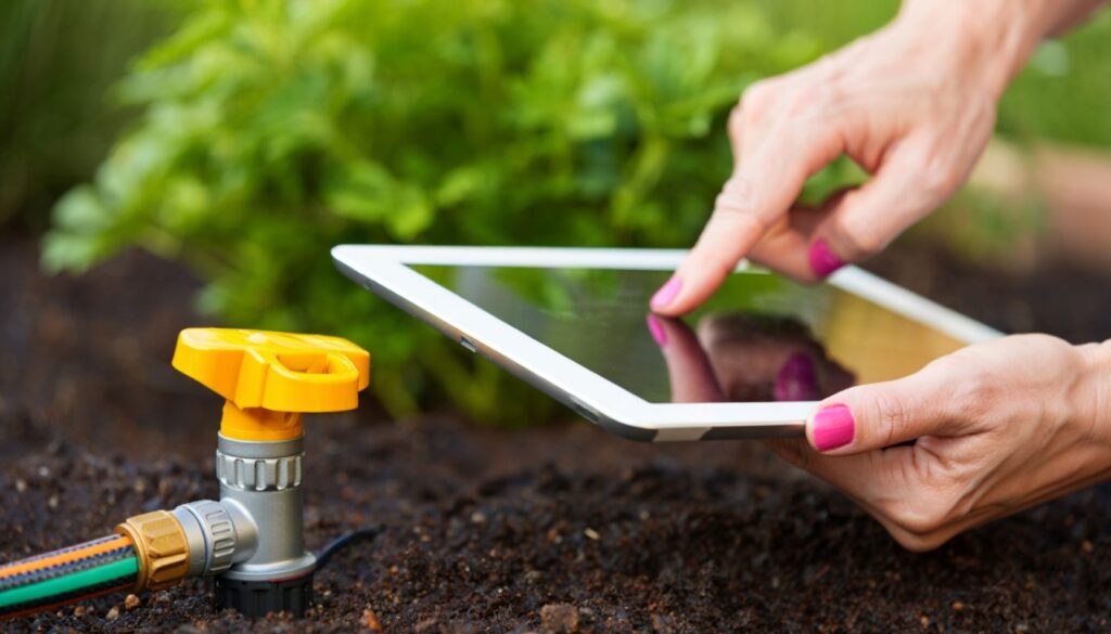 Person using a tablet in a herb garden next to a yellow hose connector.