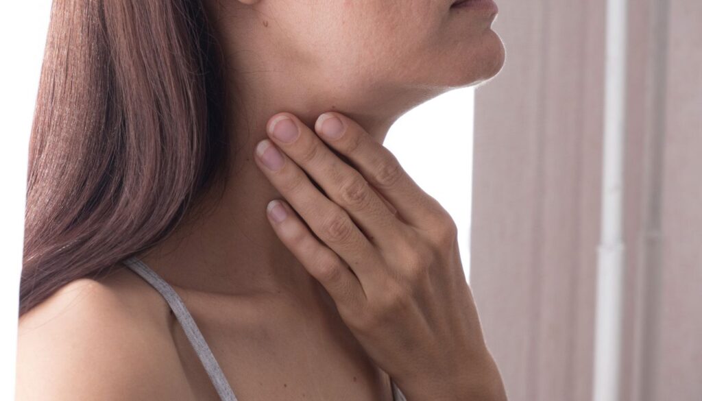 Person gently touching their neck, highlighting the thyroid area.