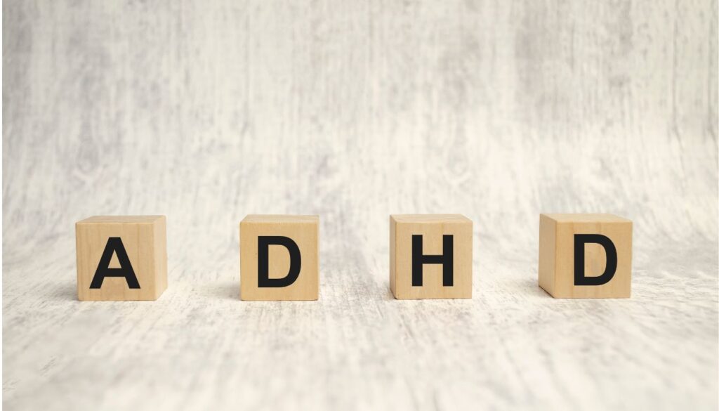 Wooden blocks spelling out ADHD on a light wooden surface.
