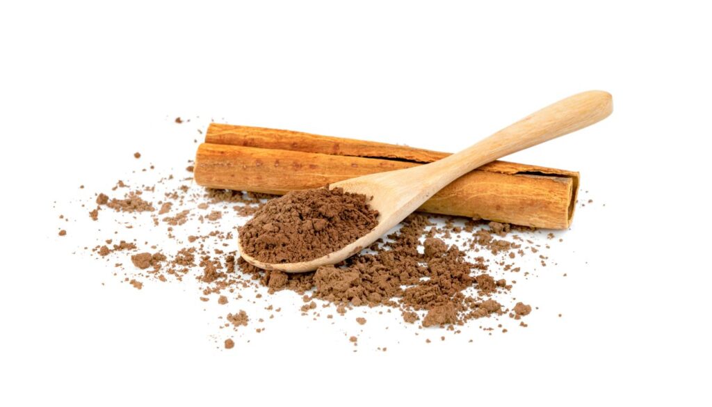 A close-up of cinnamon sticks and ground cinnamon in a wooden bowl, emphasizing its rich color and texture.