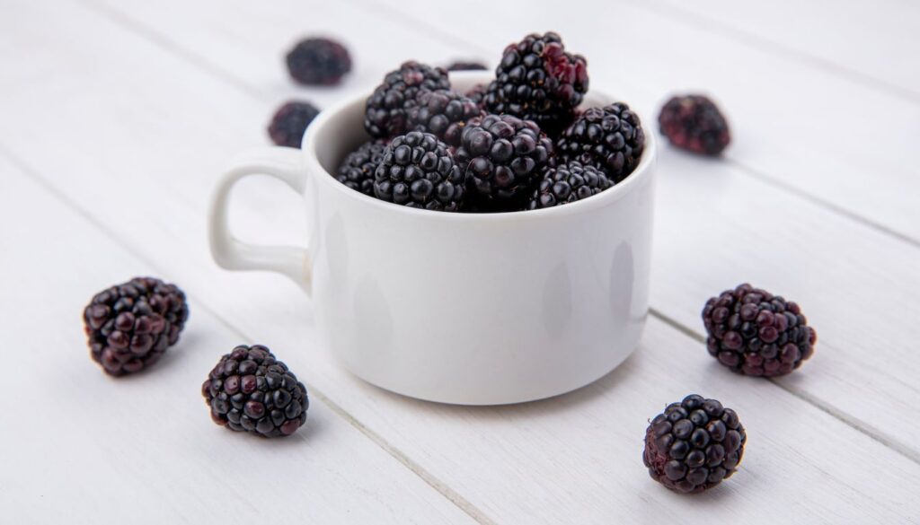 A close-up of ripe blackberries with deep purple hues, piled together, showcasing their rich texture and natural freshness.