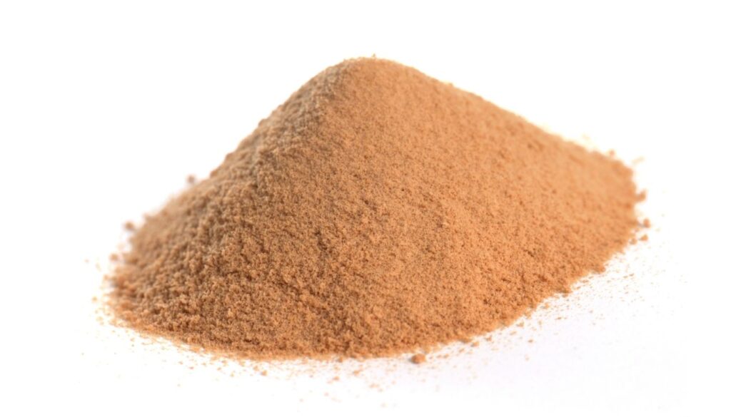 Close-up of a small mound of fine, light brown herbal tannin powder on a neutral background.