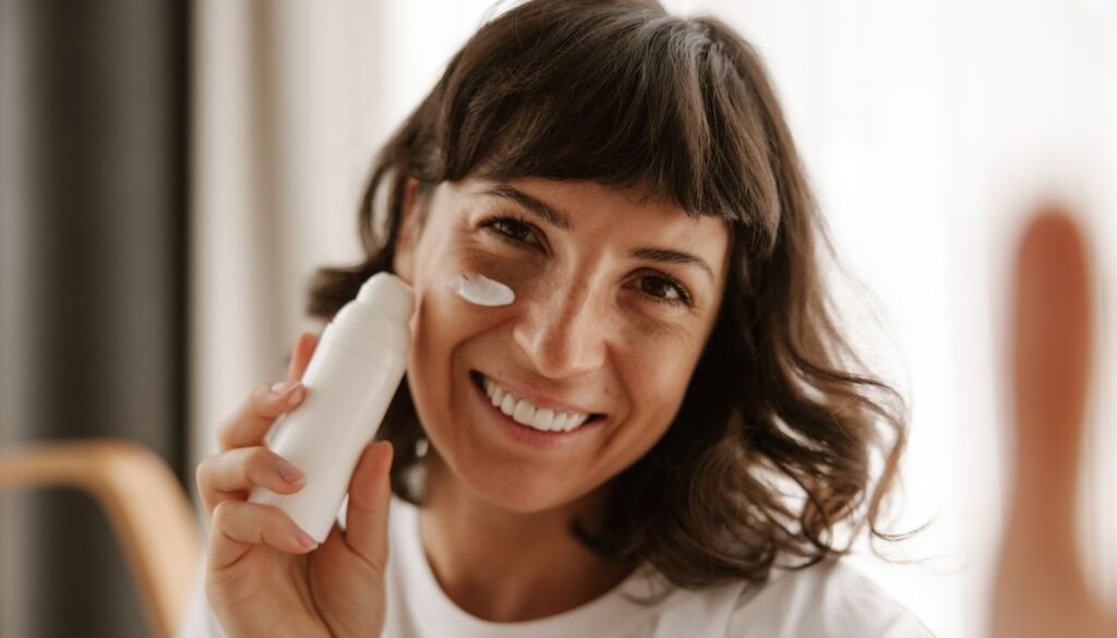 A person holding a white bottle close to their face, with a blurred background.